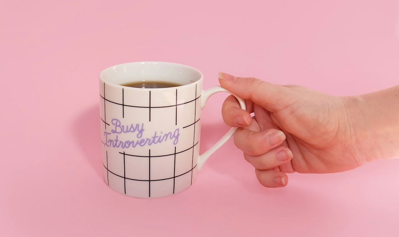 immagine buffa di una tazza colorata con la scritta "busy introverting"