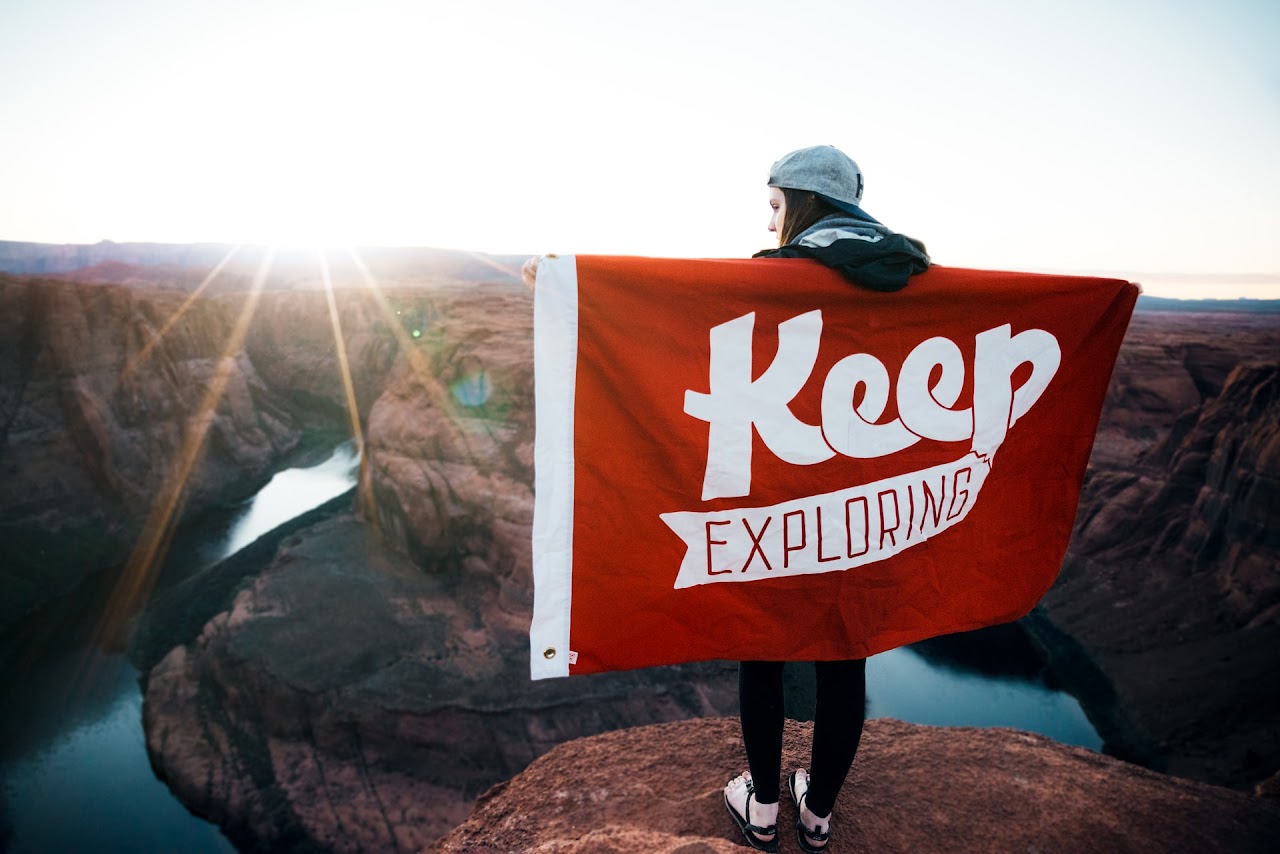 foto di una ragazza con una bandiera che dice "keep exploring"