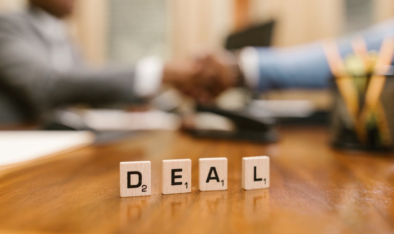 immagine di 2 persone che si stringono la mano e davanti un cartello DEAL
